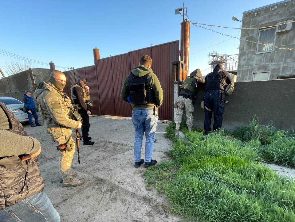 Люди у військовій формі біля воріт бази у селищі Білозерка Херсонської області
